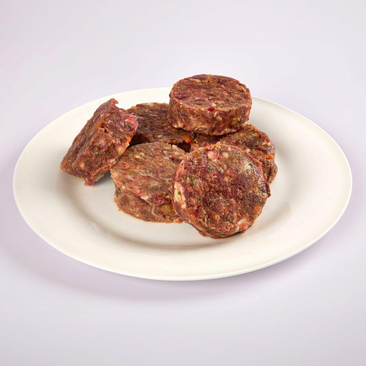 Six LUNA & me Lamb raw dog food patties on a white plate