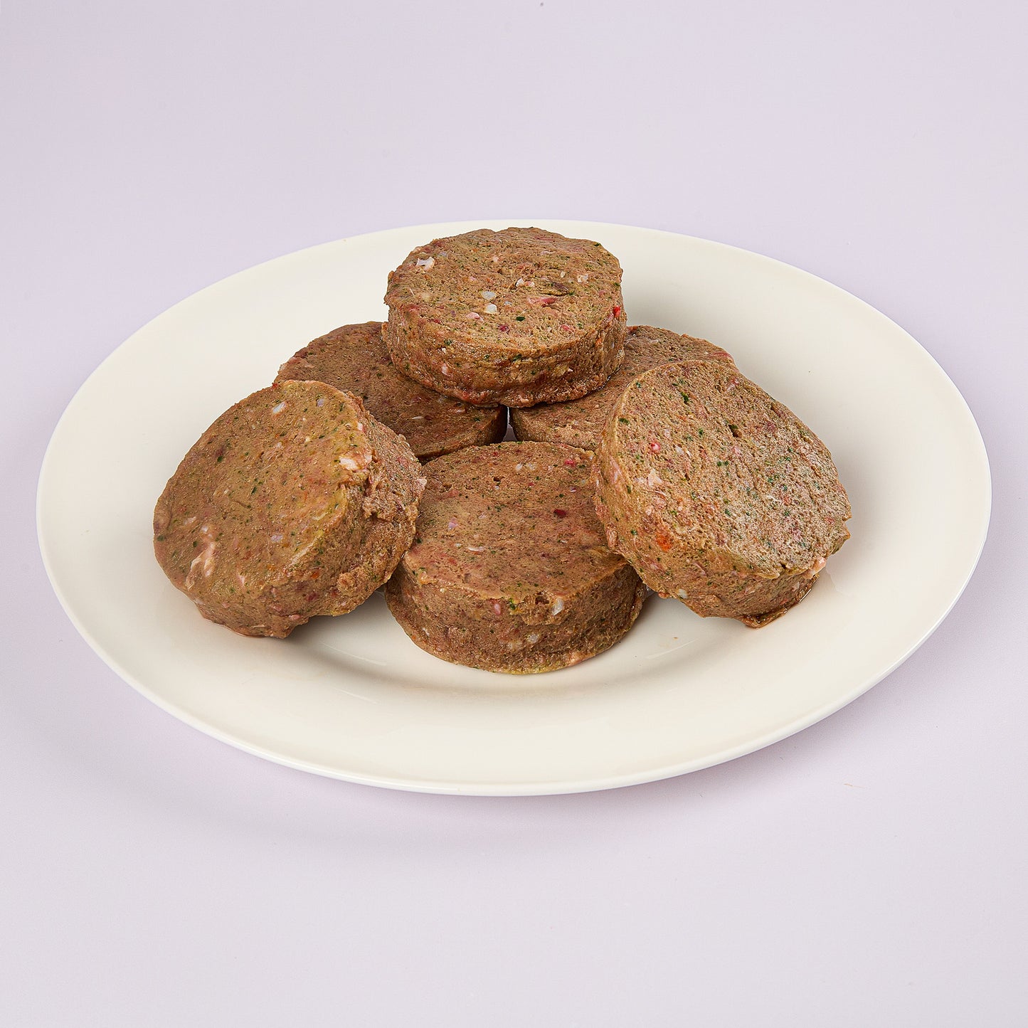 Six Puppy Power raw dog food patties on a white plate from LUNA & me