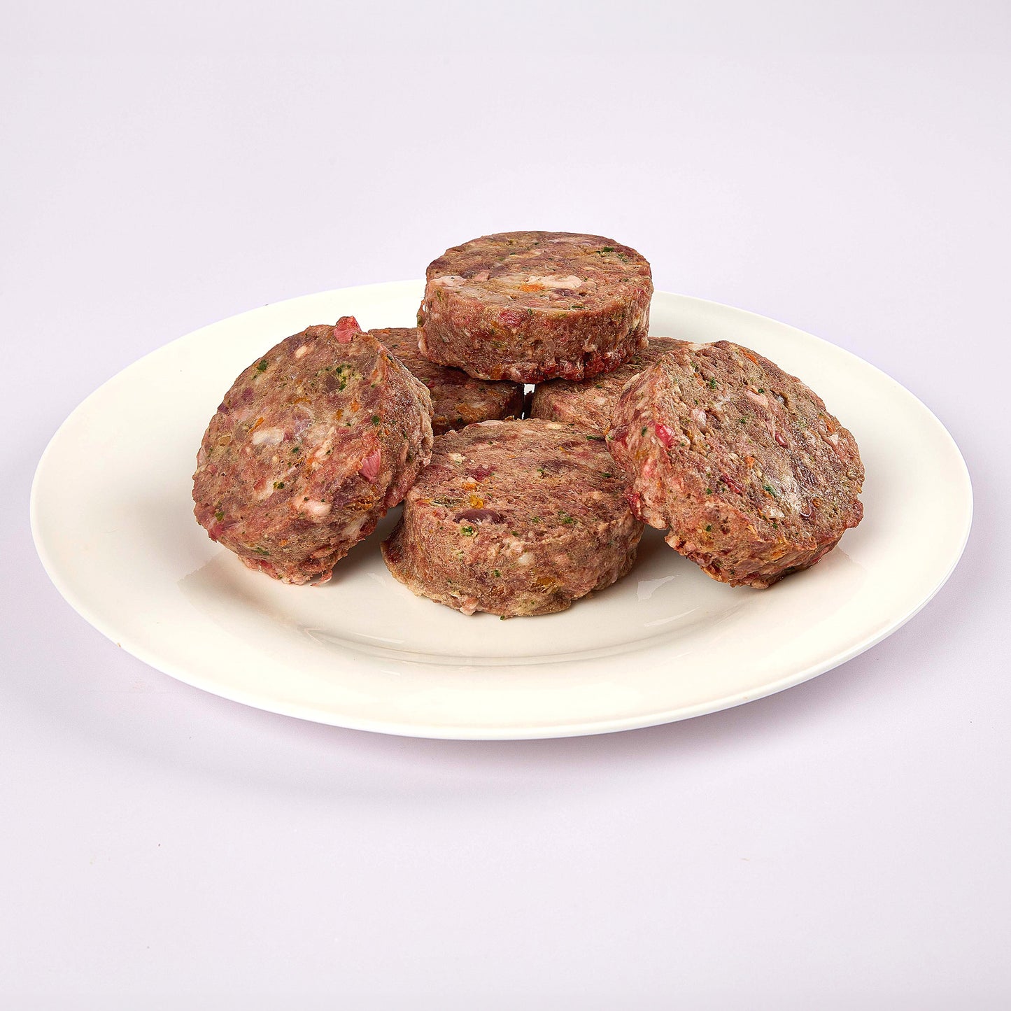 Six Lamb & Turkey raw dog food patties on a white plate from LUNA & me